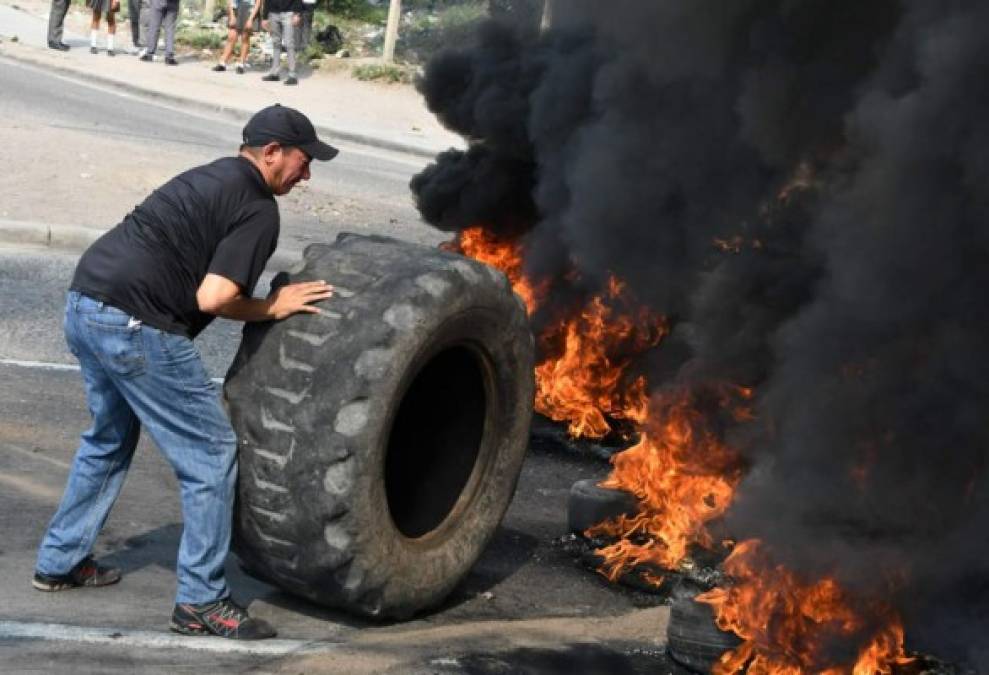 Hoy amanecieron tomados los bulevares de las principales ciudades de Honduras por decenas de maestros que protestan por los decretos de reestructuración en Educación. Pese a que el Gobierno ha asegurado que los decretos aprobados ayer por el Congreso Nacional, no buscan facilitar despidos masivos sino mejorar la calidad de atención, los gremios de Educación y Salud han mostrado su desacuerdo. En la gráfica la marcha de los maestros en Tegucigalpa, Honduras. Un manifestante lanza un neumático al fuego para bloquear una calle mientras los maestros marchan durante la protesta contra las reformas legislativas en materia de salud y educación en Tegucigalpa. Foto de AFP.