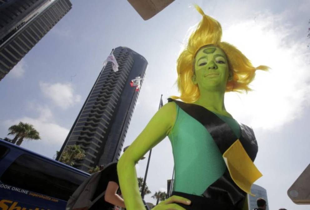 Una alienígena de piel verde y cabello amarillo chillante sonríe para la cámara.