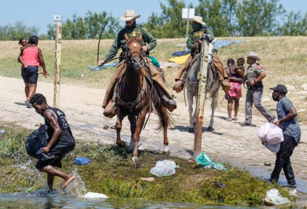 United States Border Patrol agents on horseback try to stop Haitian migrants from entering an encampment on the banks of the Rio Grande near the Acuna Del Rio International Bridge in Del Rio, Texas on September 19, 2021. - US law enforcement are attempting to close off crossing points along the Rio Grande river where migrants cross to get food and water, which is scarce in the encampment. The United States said Saturday it would ramp up deportation flights for thousands of migrants who flooded into the Texas border city of Del Rio, as authorities scramble to alleviate a burgeoning crisis for President Joe Biden's administration. (Photo by PAUL RATJE / AFP)