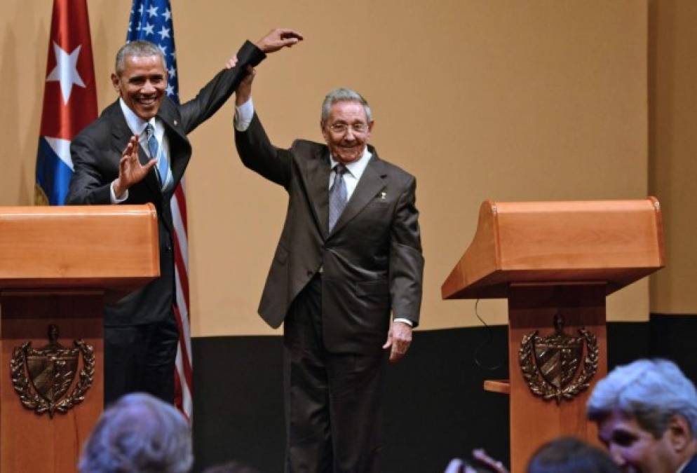 Raúl Castro levanta el brazo a Barack Obama como muestra de satisfacción por su visita.