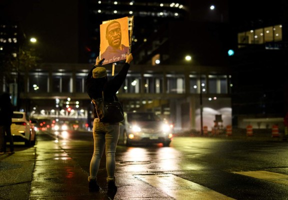 MINNEAPOLIS, MN - APRIL 9: A woman holds up a portrait of George Floyd as people gather outside the Hennepin County Government Center on April 9, 2021 in Minneapolis, Minnesota. People demanding justice for George Floyd gathered tonight outside the Government Center, where the trial of former Minneapolis police officer Derek Chauvin has been ongoing for the past two weeks. Stephen Maturen/Getty Images/AFP (Photo by Stephen Maturen / GETTY IMAGES NORTH AMERICA / Getty Images via AFP)