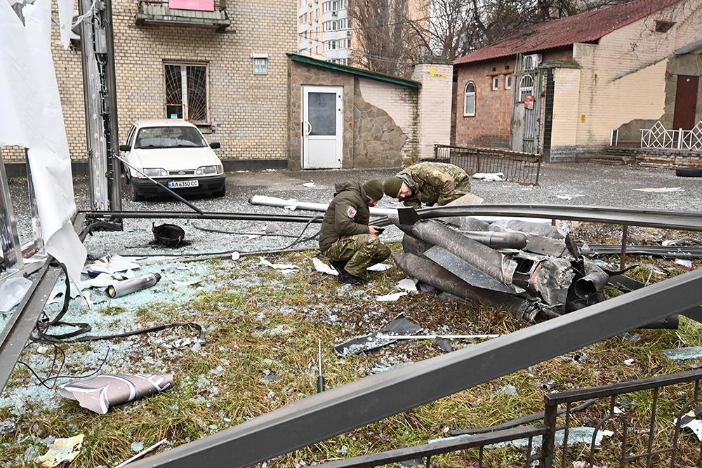 La policía y el personal de seguridad inspeccionan los restos de un proyectil en una calle de Kiev el 24 de febrero de 2022.