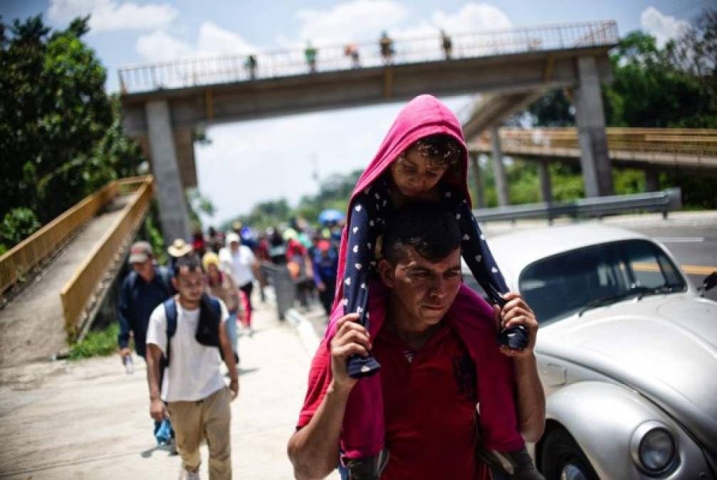 Cansada del camino, una niña es cargada por su padre antes de cruzar la frontera entre Guatemala y México.