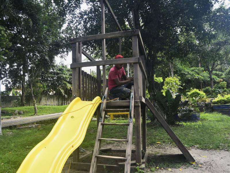 Un joven le da mantenimiento a los juegos del parque infantil como parte de los trabajos de remodelación.