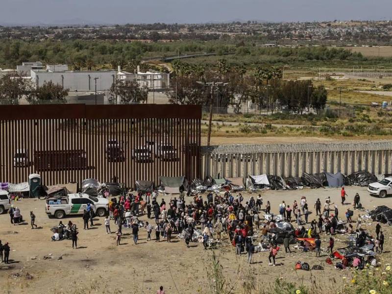Decenas de migrantes reunidos en un punto fronterizo entre México y Estados Unidos.