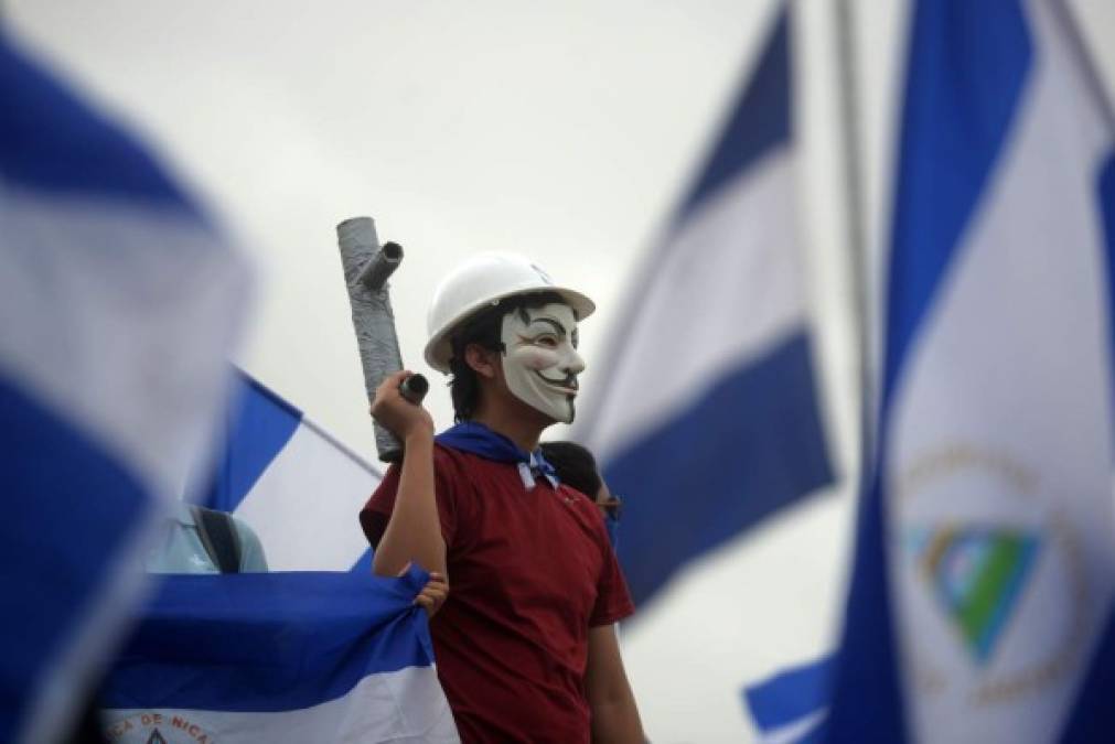 A student wearing a Guy Fawkes mask holds a homemade mortar during a march demanding the resignation of Nicaraguan President Daniel Ortega and his wife, Vice-President Rosario Murillo, in Managua on July 23, 2018.<br/>Ortega refused Monday to bow to protesters' demands that he step down, vowing in an interview with US television that he will see through his current term until 2021. / AFP PHOTO / MARVIN RECINOS
