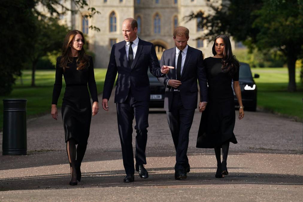 Vestidos de riguroso luto, los nuevos príncipes de Gales, William y Kate, y los duques de Sussex, Harry y Meghan, miraron las flores, las tarjetas y dibujos de niños depositados ante el castillo de Windsor, antes de acercarse a los súbditos allí reunidos. 