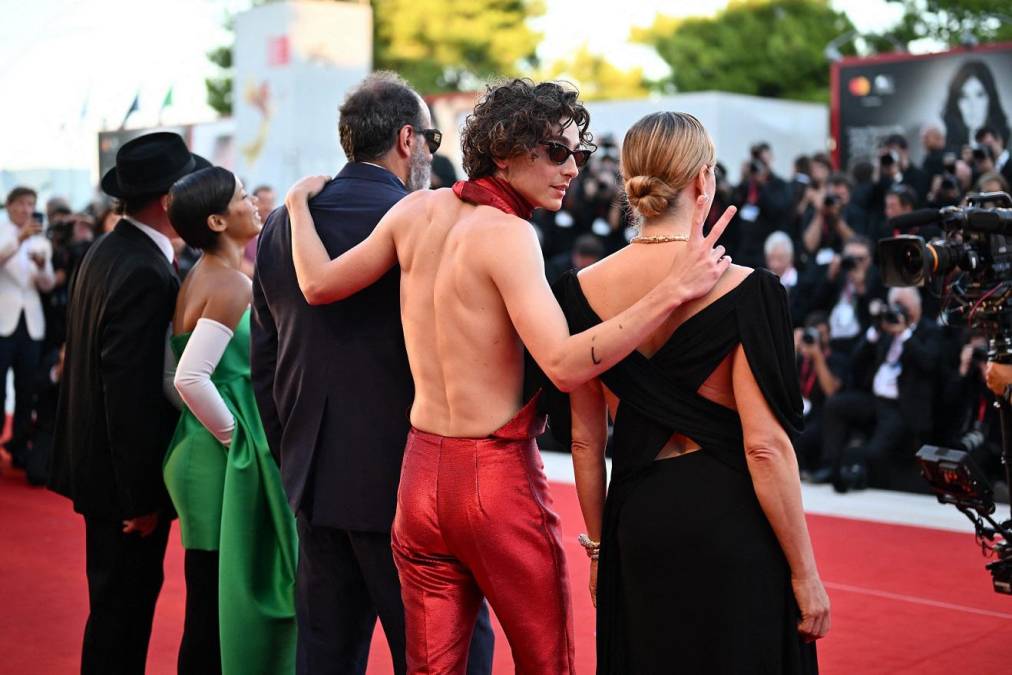 Chalamet desató una auténtica locura entre sus fans al aparecer con gafas de sol y vestido con un entallado y brillante conjunto rojo compuesto por pantalón y una parte superior con un foulard que solo cubría su pecho pero dejaba la espalda totalmente descubierta.