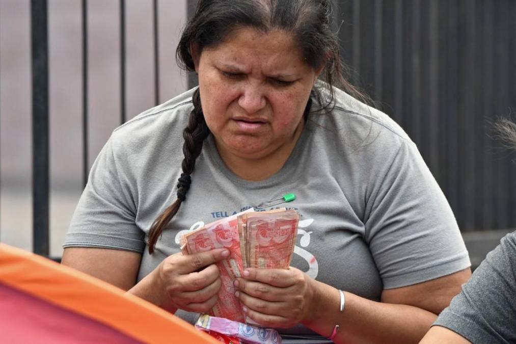 Una migrante venezolana cuenta el dinero hondureño recolectado en la calle de la capital hondureña.