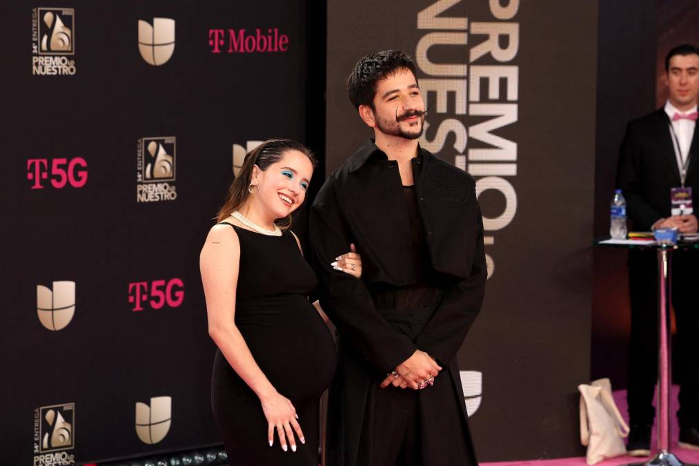 Camilo, uno de los más nominados con 10, y su esposa Eva Luna Montaner hicieron un breve desfile por la “Alfombra Magenta”, los dos de negro y emocionados por la inminente llegada de Índigo, su primer bebé juntos. 