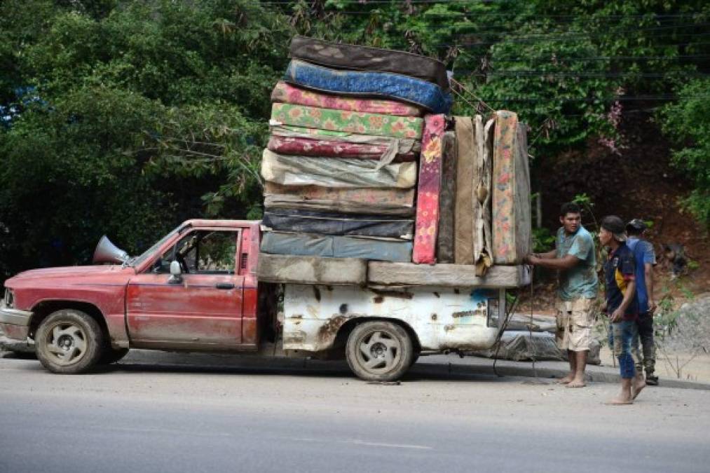 Hombres cargan colchones en una camioneta pick-up luego del paso del huracán Eta en el municipio de Villanueva, departamento de Cortés.