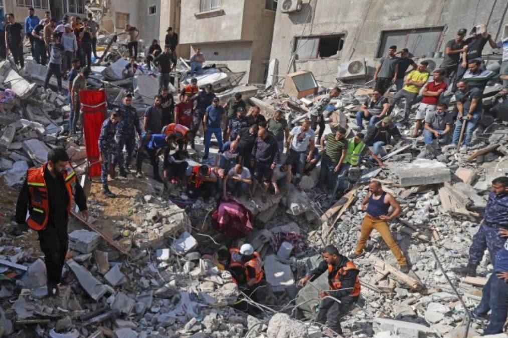 TOPSHOT - Palestinian paramedics search for survivors under the rubble of a destroyed building in Gaza City on May 16, 2021, following massive Israeli bombardment of the Hamas-controlled enclave. - Israel's army said it had bombed the home of the political leader of Islamist group Hamas in the Gaza Strip, as the UN Security Council was to meet amid global alarm about the escalating conflict. (Photo by MAHMUD HAMS / AFP)