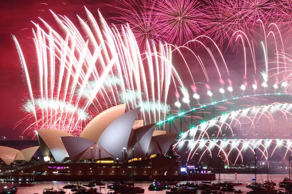 Los fuegos artificiales de Nochevieja iluminan el cielo sobre la Ópera de Sídney y el Puente Harbour durante la exhibición de fuegos artificiales en Sídney el 1 de enero de 2023.