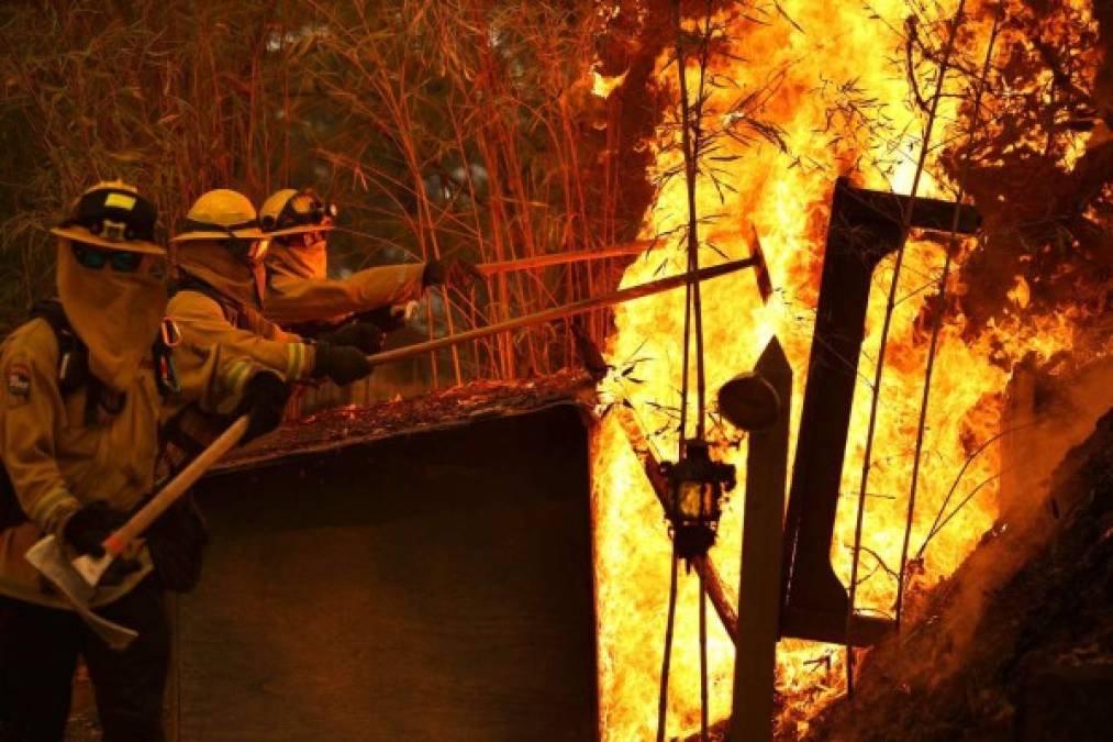 ST. HELENA, CALIFORNIA - SEPTEMBER 27: Cal Fire firefighters push over a burning dog house as they battle the Glass Fire on September 27, 2020 in St. Helena, California. The fast moving Glass fire has burned over 1,000 acres and has destroyed homes. Much of Northern California is under a red flag warning for high fire danger through Monday evening. Justin Sullivan/Getty Images/AFP<br/><br/>== FOR NEWSPAPERS, INTERNET, TELCOS & TELEVISION USE ONLY ==<br/><br/>