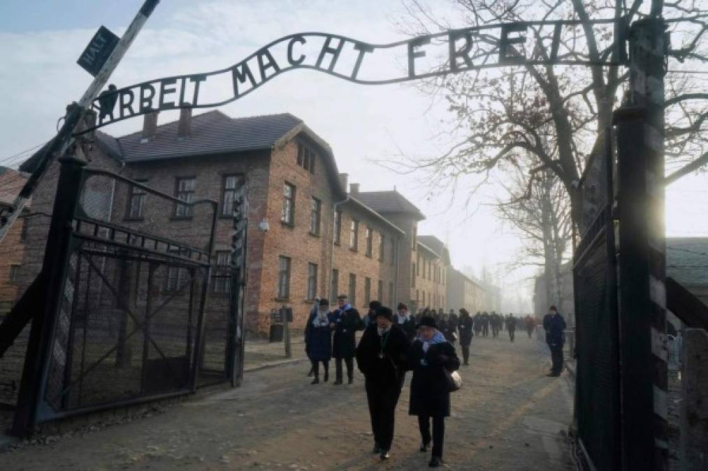 (FILES) In this file photo taken on January 27, 2020 Holocaust survivors walk below the gate with its inscription 'Work sets you free' after a wreath laying at the death wall at the memorial site of the former German Nazi death camp Auschwitz during ceremonies to commemorate the 75th anniversary of the camp's liberation in Oswiecim, Poland. - Events to commemorate the 76th anniversary of the camp's liberation in Oswiecim, Poland, on January 27, 2021, which will be held online this year due to the ongoing novel coronavirus Covid-19 pandemic, will focus on the camp's some 200,000 child victims. (Photo by JANEK SKARZYNSKI / AFP)