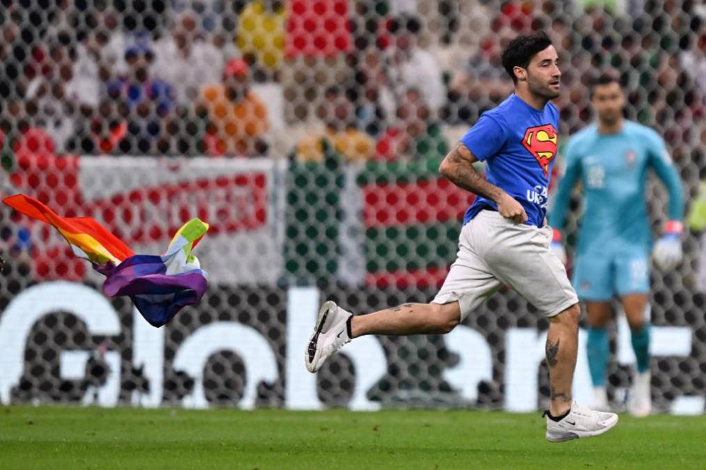 Un individuo con una bandera arcoíris y una camiseta con un mensaje a favor de las mujeres iraníes y en contra de la invasión rusa en Ucrania ingresó al césped durante el partido entre Portugal y Uruguay .