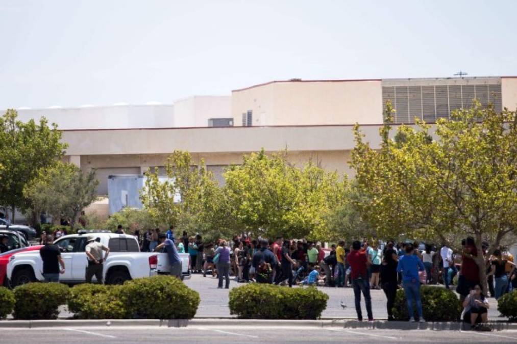 Individuals that were evacuated sit in a parking lot across from a Wal-Mart where a shooting occurred at Cielo Vista Mall in El Paso, Texas, Saturday, Aug. 3, 2019. - A shooting at a Walmart store in Texas left multiple people dead. At least one suspect was taken into custody after the shooting in the border city of El Paso, triggering fear and panic among weekend shoppers as well as widespread condemnation. It was the second fatal shooting in less than a week at a Walmart store in the US and comes after a mass shooting in California last weekend. (Photo by Joel Angel JUAREZ / AFP)
