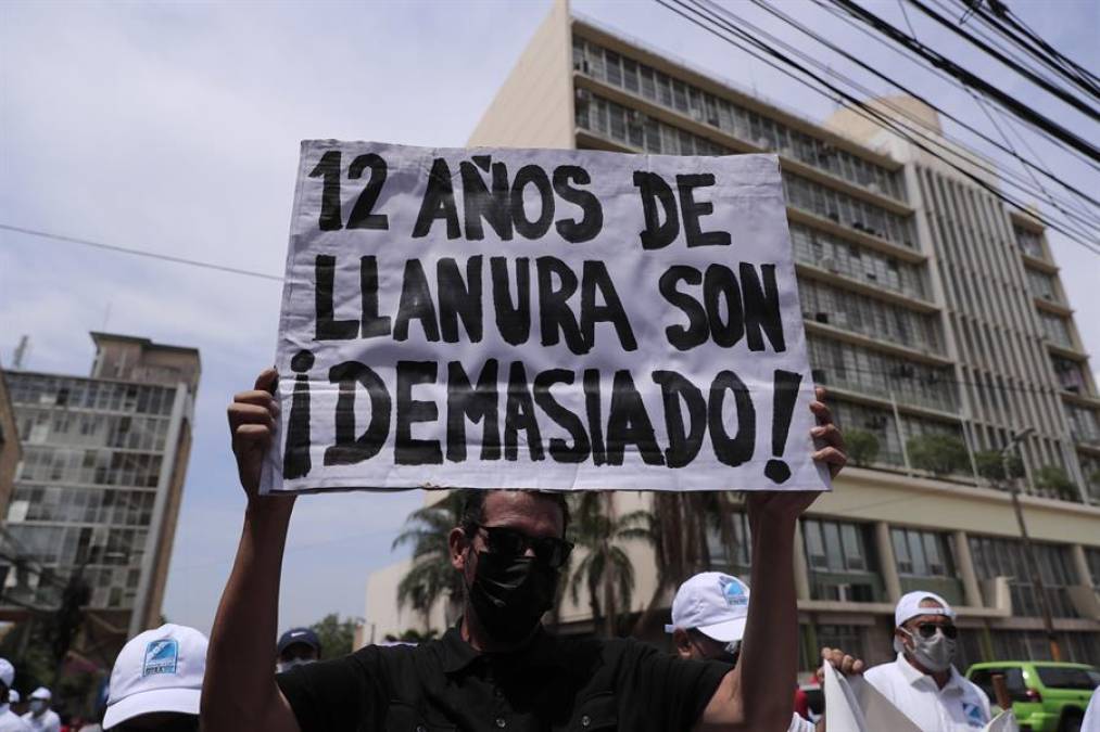 Un hondureño sostiene una pancarta recordando a los gobiernos de los últimos 12 años.