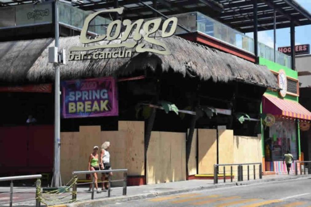 Una pareja de turistas pasa junto a un bar cerrado en Cancún, estado de Quintana Roo, México, el 28 de marzo de 2020.