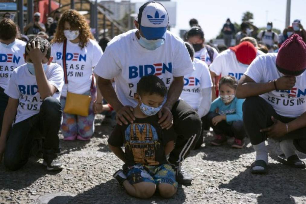 Yadiel García y su padre Fabricio, de Honduras, se arrodillan mientras oran durante una manifestación de migrantes exigiendo políticas migratorias más claras de Estados Unidos. AFP