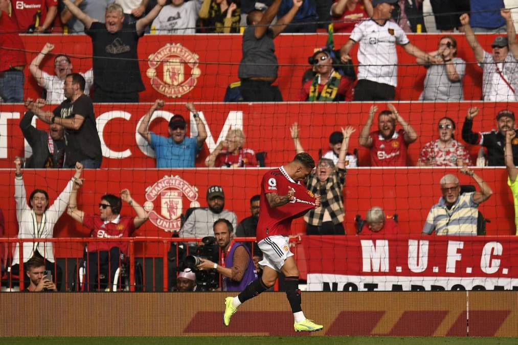 La euforia de Antony, señalando el escudo del Manchester United, y al fondo celebran los aficionados.
