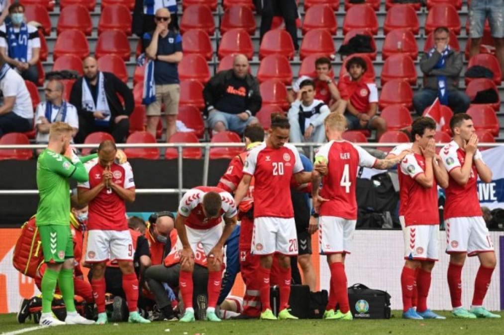 Denmark's players gather around teammate Denmark's midfielder Christian Eriksen after collapsing on the pitch during the UEFA EURO 2020 Group B football match between Denmark and Finland at the Parken Stadium in Copenhagen on June 12, 2021. (Photo by Jonathan NACKSTRAND / various sources / AFP)