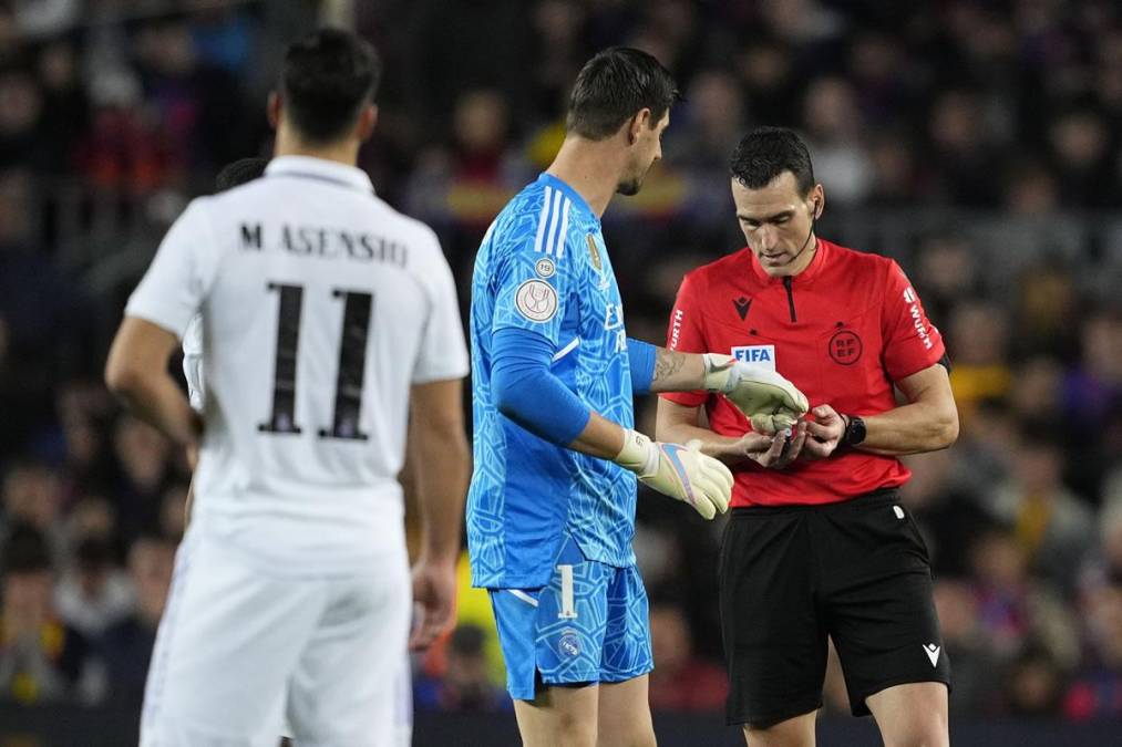 El guardameta del Real Madrid, Thibaut Courtois, le da al árbitro Juan Martínez Munuera los objetos arrojados al campo de juego por la afición del Barcelona en el Clásico.