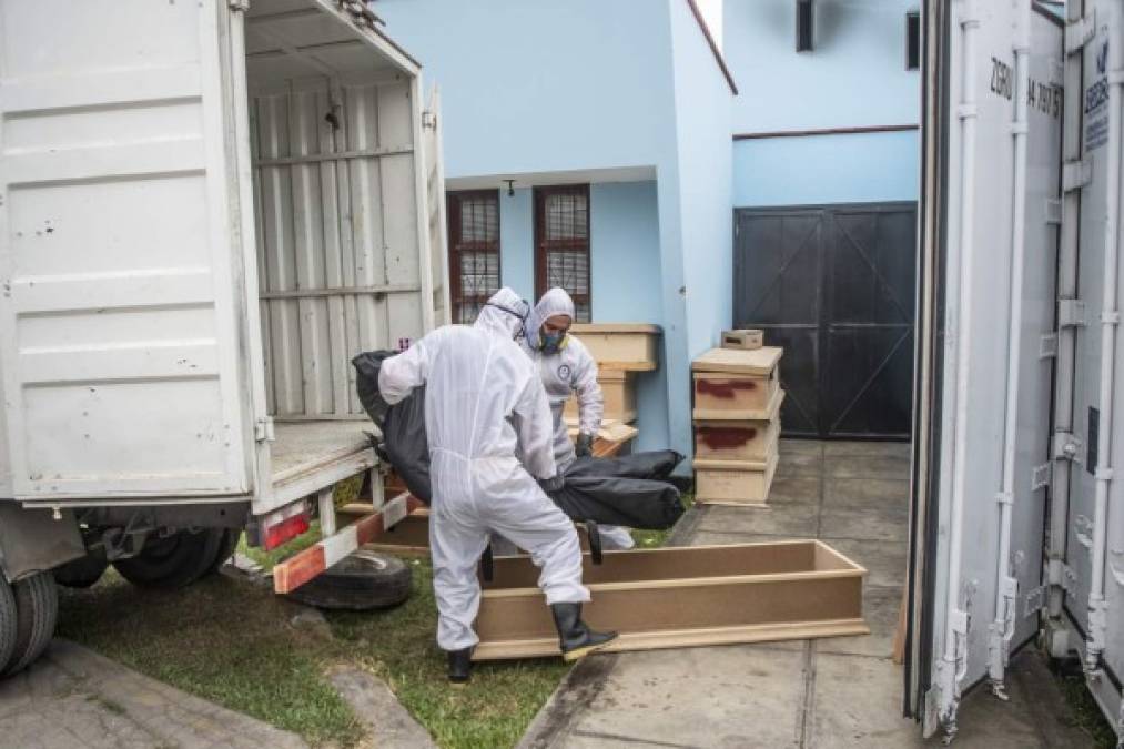 Workers carry a bag with the body of a COVID-19 victim out of a refrigerated container before its cremation at the El Angel crematorium, in Lima on May 21, 2020 - Peru has become the second Latin American country after Brazil to reach 100,000 coronavirus cases, according to health ministry figures out Wednesday. (Photo by Ernesto BENAVIDES / AFP)