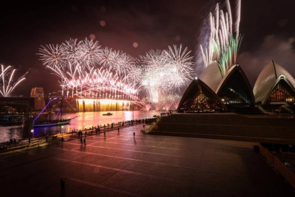 AUSTRALIA. Se puede ver una explanada de la Ópera de Sídney abandonada frente a los fuegos artificiales que estallan desde el Puente del Puerto de Sídney.
