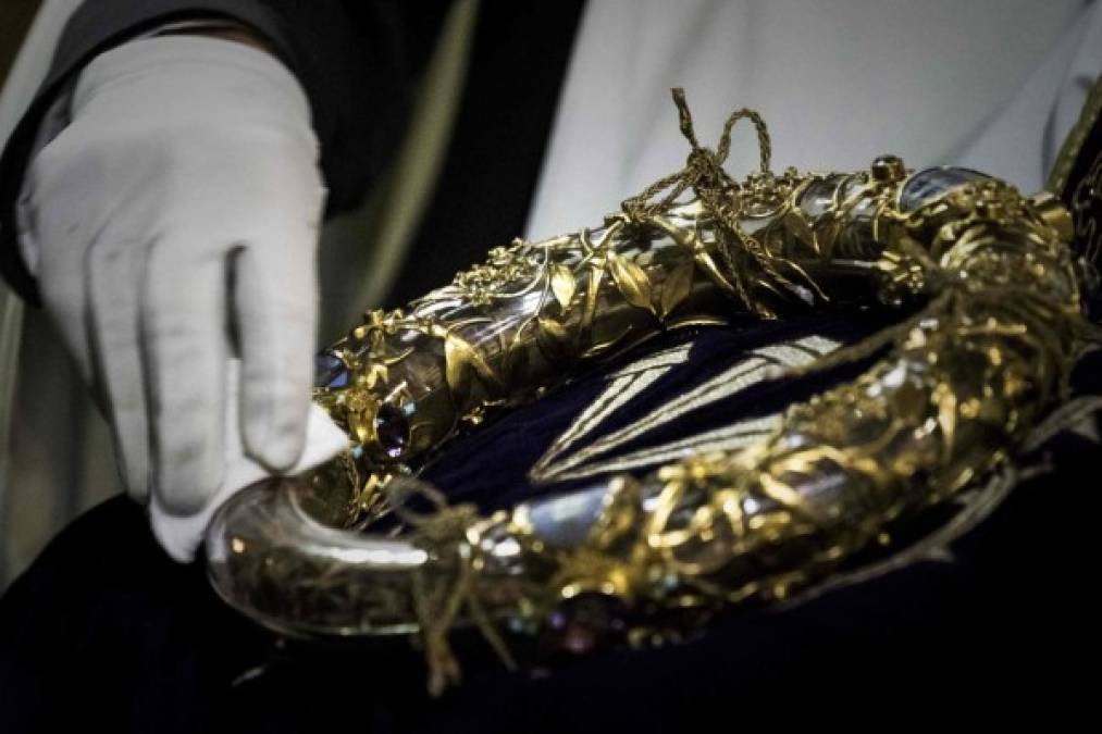 (FILES) In this file photo taken on April 14, 2017 shows a priest wiping the Crown of Thorns, a relic of the passion of Christ- at the Notre-Dame Cathedral in Paris. - A colossal fire swept through the famed Notre-Dame Cathedral in central Paris on April 15, 2019, causing a spire to collapse and threatening to destroy the entire masterpiece and its precious artworks. The fire, which began in the early evening, sent flames and huge clouds of grey smoke billowing into the Paris sky as stunned Parisians and tourists watched on in sheer horror. (Photo by Philippe Lopez / AFP)