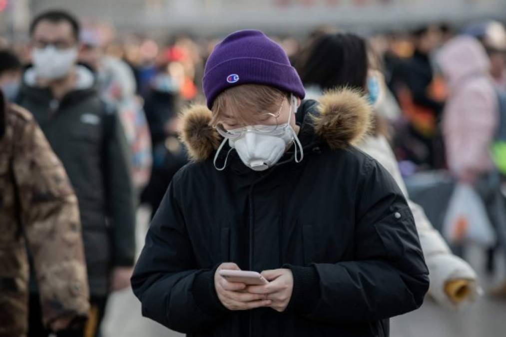 People wearing protective masks arrive at Beijing railway station to head home for the Lunar New Year on January 21, 2020. - China has confirmed human-to-human transmission in the outbreak of a new SARS-like virus as the number of cases soared and the World Health Organization said it would consider declaring an international public health emergency. (Photo by NICOLAS ASFOURI / AFP)