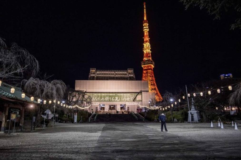 La Torre de Tokio (R) se ilumina mientras la gente camina en el Parque Shiba en la víspera de Año Nuevo en Tokio el 31 de diciembre de 2020.<br/>Philip FONG / AFP
