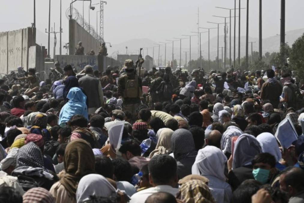 Afghans gather on a roadside near the military part of the airport in Kabul on August 20, 2021, hoping to flee from the country after the Taliban's military takeover of Afghanistan. (Photo by Wakil KOHSAR / AFP)