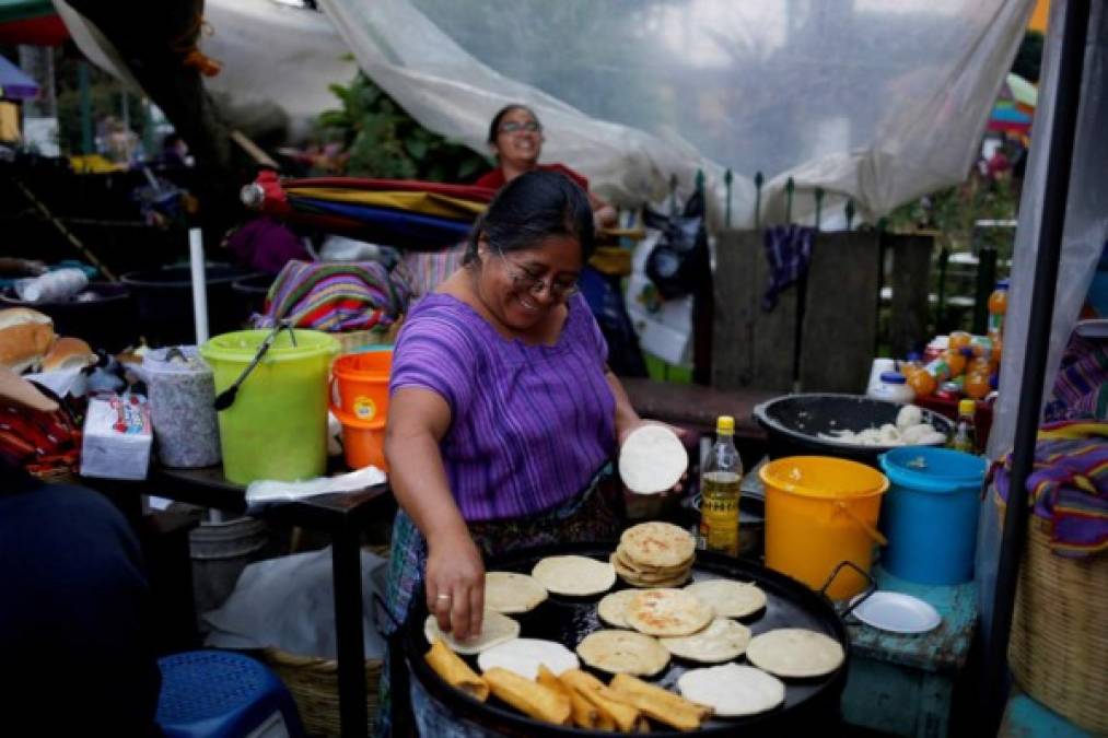 Una mujer cocina tortillas y pupusas frente a un centro de votación en el municipio indígena de San Juan Sacatepéquez. Foto: EFE