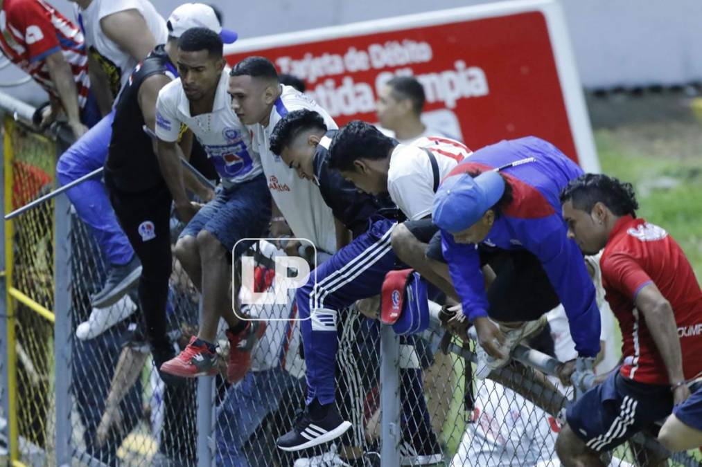 Aficionados olimpistas se saltaron el alambrado del sector preferencial para buscar a los hinchas del Motagua.