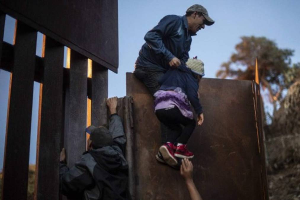 Central American migrants who have been travelling in a caravan hoping to get to the United States, climb the metal barrier separating Mexico and the US to cross from Playas de Tijuana in Mexico into the United States, on December 2, 2018. - Thousands of Central American migrants, mostly Hondurans, have trekked for over a month in the hopes of reaching the United States. (Photo by Pedro PARDO / AFP)