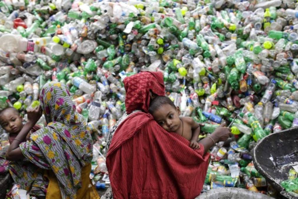 BANGLADESH. La vida entre botellas de plástico. Dos mujeres con sus hijos trabajan en una planta de reciclaje de botellas de plástico PET (polyethylene terephtalate) en Dhaka. Foto: EFE/Abir Abdullah