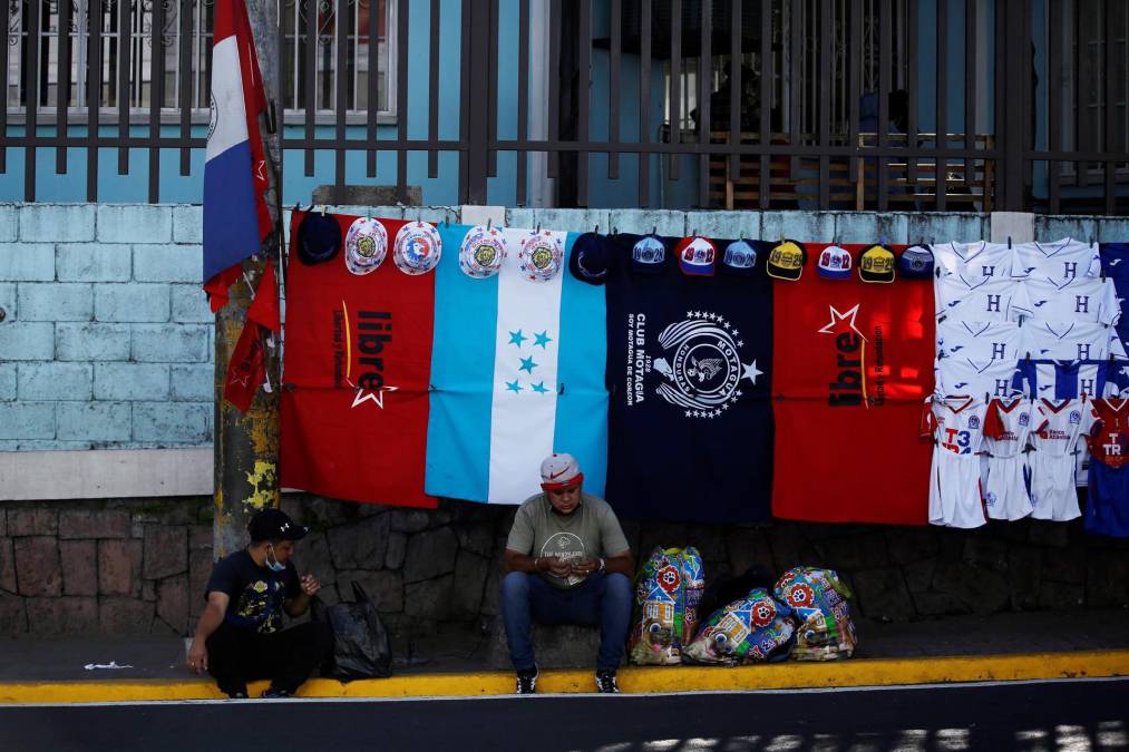 Dos hombres venden camisetas, banderas y accesorios en los alrededores del Estadio Nacional Tiburcio Carías Andino, donde se realizará este jueves la ceremonia de investidura de la izquierdista Xiomara Castro como presidenta de Honduras, hoy, en Tegucigalpa (Honduras). EFE/ Bienvenido Velasco