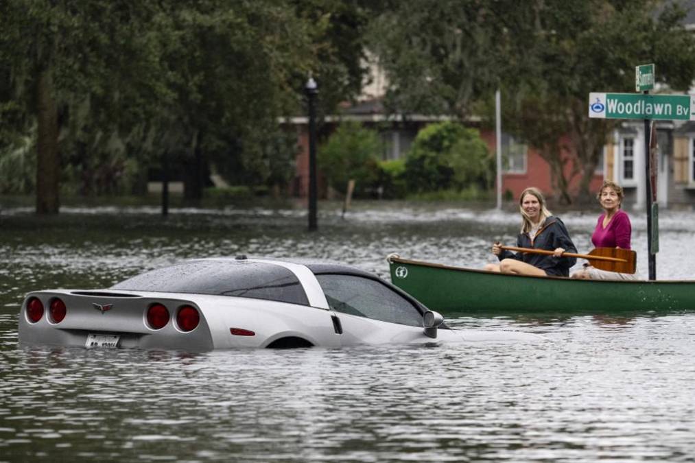 La mujeres reman en una canoa junto a un Chevy Corvette sumergido en el agua después del huracán Ian en Orlando, Florida.