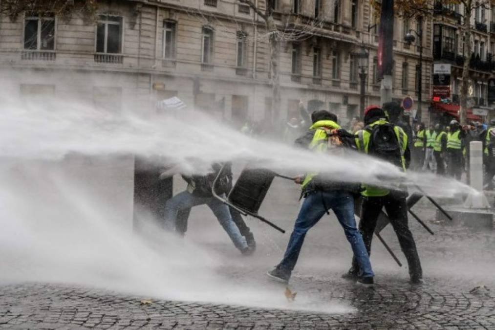 La avenida parisina fue cortada por los manifestantes, que arrojaron proyectiles, montaron barricadas y quemaron mobiliario urbano, mientras la policía antidisturbios intentaba hacerlos retroceder con gases lacrimógenos y camiones equipados con cañones de agua.