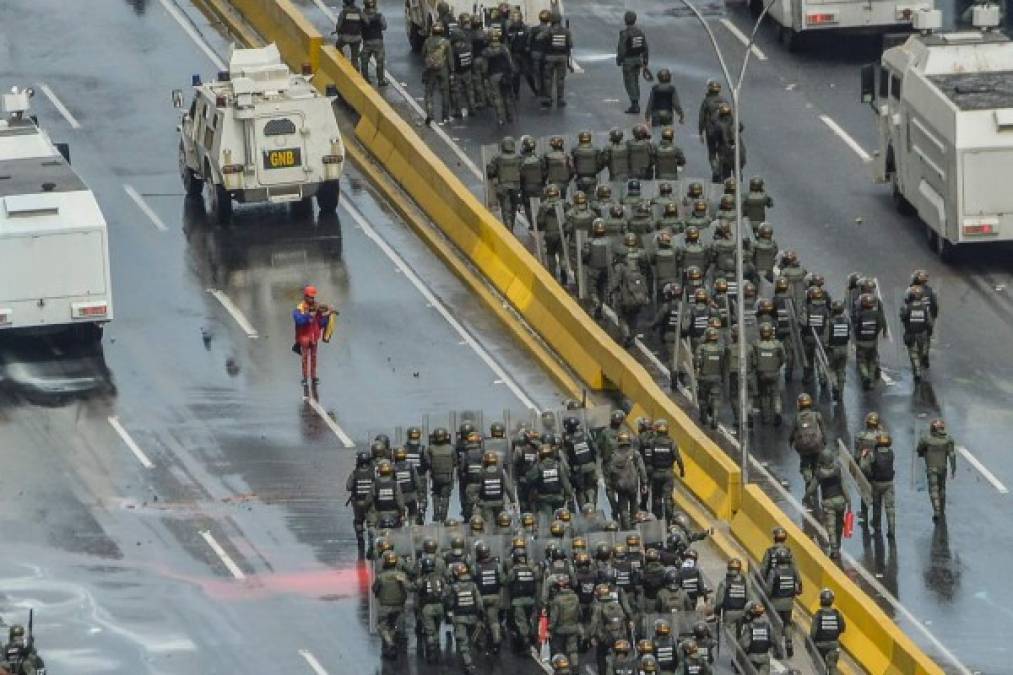 Escuadrones de antimotines se encaminan a enfrentarse a los manifestantes opositores.