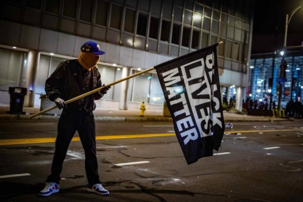 A protester wearing a Black Panther jacket and holding a 'Black Lives Matter' flag faces off with riot police in Rochester, New York, on September 5, 2020, on the fourth night of protest following the release of video showing the death of Daniel Prude. - Prude, a 41-year-old African American who had mental health issues, died of asphyxiation after police arrested him on March 23, 2020, in Rochester. (Photo by Maranie R. STAAB / AFP)