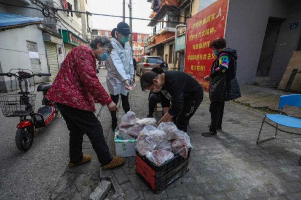 People, wearing face masks as a preventive measure against the spread of the COVID-19 novel coronavirus, are seen on a street in a neighborhood closed off by barriers in Wuhan, China's central Hubei province on April 20, 2020. - China's economy shrank for the first time in decades last quarter as the coronavirus paralysed the country, in a historic blow to the Communist Party's pledge of continued prosperity in return for unquestioned political power. The main access to the neighbourhood is on another street where workers take the temperatures of people and maintain the Wuhan health code. (Photo by Hector RETAMAL / AFP)