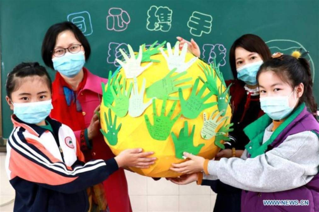 Los estudiantes y sus maestros muestran un modelo de la Tierra durante una actividad que pide la protección de la Tierra y el medio ambiente en una escuela en la ciudad de Huzhou, provincia de Zhejiang, este de China.