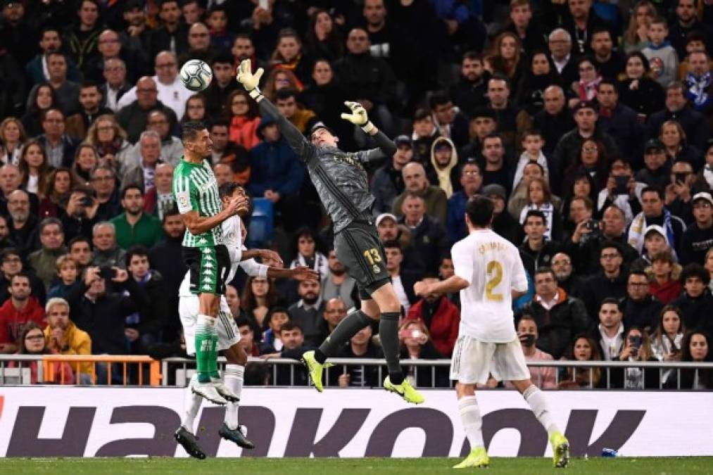 El portero Thibaut Courtois salta para agarrar el balón ante el acecho de un jugador del Betis.