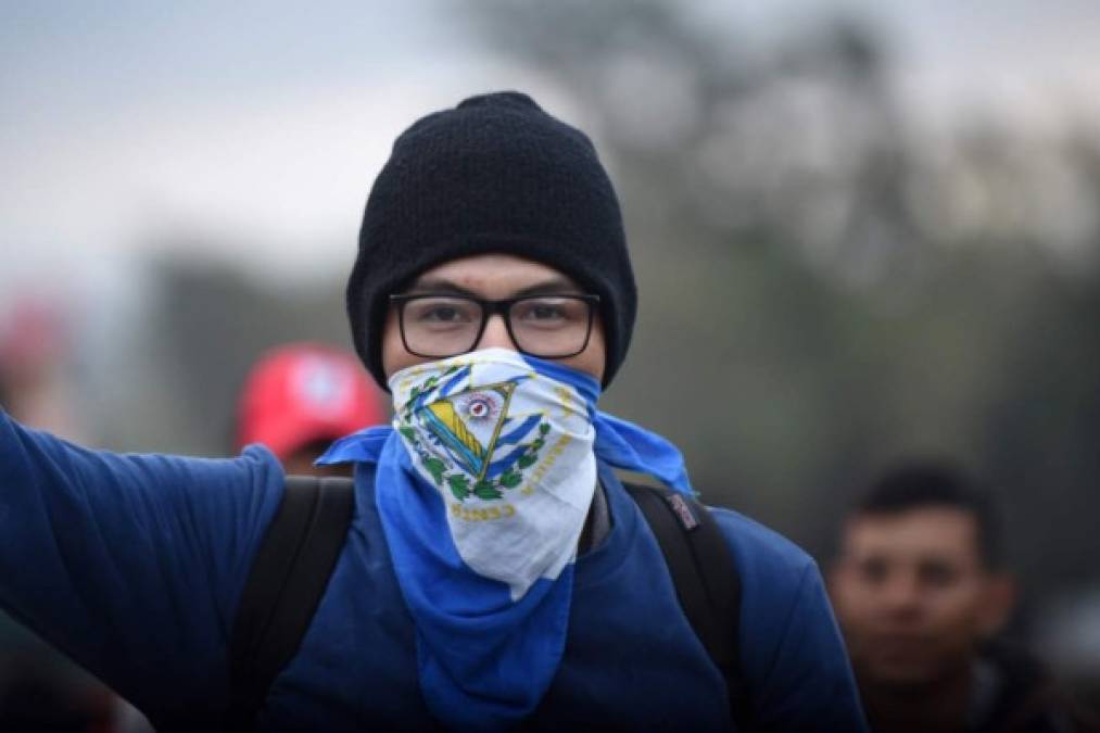 A la caravana migrante de hondureños se están sumando también salvadoreños. Un joven porta la bandera salvadoreña en su rostro.