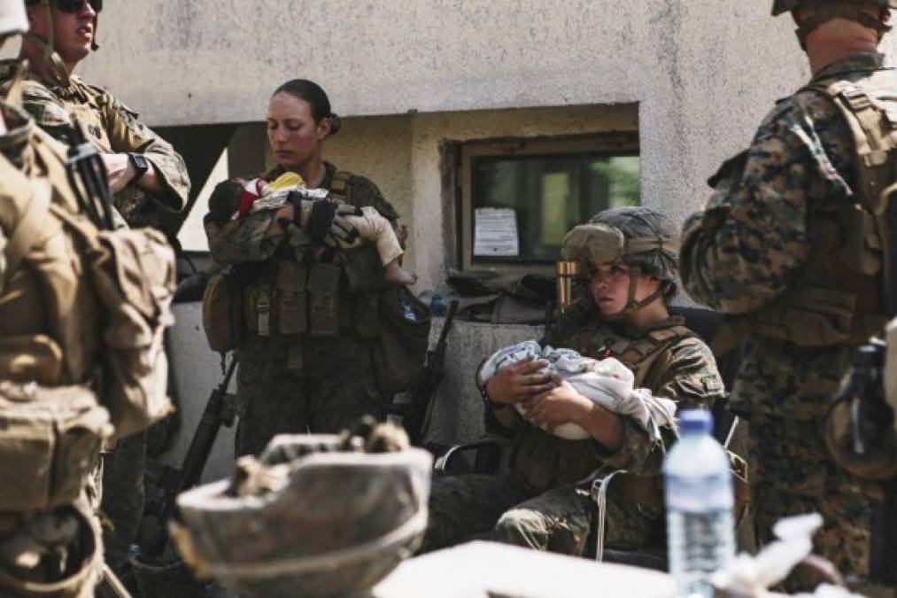 In this image courtesy of the US Central Command Public Affairs, US Marines assigned to the 24th Marine Expeditionary Unit calm infants during an evacuation at Hamid Karzai International Airport in Kabul on August 20, 2021. - A Pentagon official confirmed Friday that US evacuation operations from Kabul's airport have been stalling because the receiving base in Qatar is overflowing and could not receive evacuees. 'There has been a considerable amount of time today where there haven't been departures,' Brigadier General Dan DeVoe of the US Air Mobility Command told reporters. (Photo by Isaiah CAMPBELL / US Central Command Public Affairs / AFP) / RESTRICTED TO EDITORIAL USE - MANDATORY CREDIT 'AFP PHOTO / US Marine Corps / Sgt. Isaiah Campbell' - NO MARKETING - NO ADVERTISING CAMPAIGNS - DISTRIBUTED AS A SERVICE TO CLIENTS