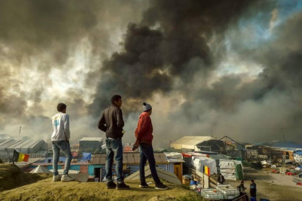 FRANCIA. Tras el desmantelamiento. Varios migrantes observan cómo el humo se eleva en el campamento conocido como “La Jungla”, en Calais. Foto: AFP/Philippe Huguen