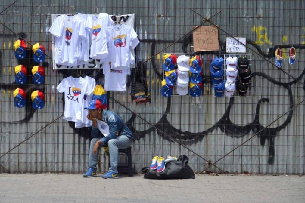 Un vendedor de camisetas y gorras con motivos alusivos a la bandera venezolana ofrece su mercadería cerca del lugar en el que se reunen los manifestantes contra el gobierno.