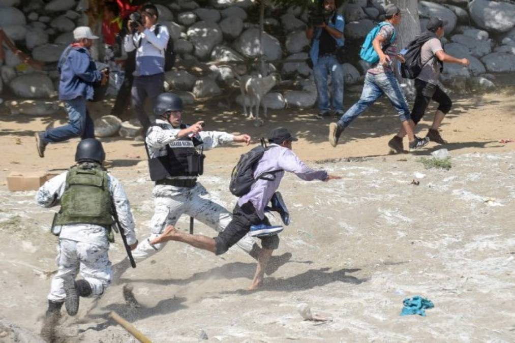 A Central American migrant - part of a caravan of mostly Hondurans travelling to the US- is tackeld by a member of Mexico's National Guaed after crossing the Suichate River, the natural border between Tecun Uman in Guatemala and Ciudad Hidalgo in Mexico, on January 20, 2020. - Hundreds of Central Americans from a new migrant caravan tried to enter Mexico by force Monday by crossing the river that divides the country from Guatemala, prompting the National Guard to fire tear gas, an AFP correspondent said. (Photo by Johan ORDONEZ / AFP)